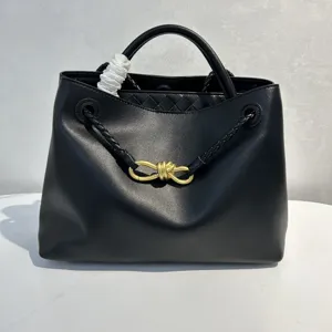 Black leather handbag with metallic knot hardware and woven interior design for women.