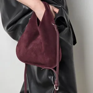 Detail view of a stylish burgundy suede triangle dumpling handbag with slim strap for women.