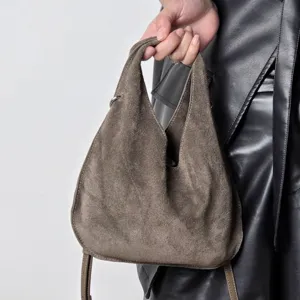 Suede triangle dumpling handbag detail shot, showing the texture and handle design.