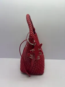 Red woven leather bucket bag detail showing intricate intrecciato texture and star charm.
