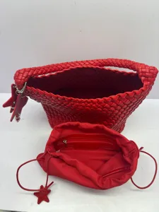 Red woven leather handbag detail showing intrecciato handle and inner pouch structure.