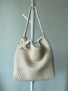 Detailed view of cream white woven leather shoulder bag with star charm and large capacity design.