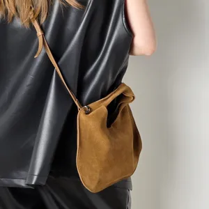 Detail view of the brown suede triangular crossbody bag, showcasing premium leather.