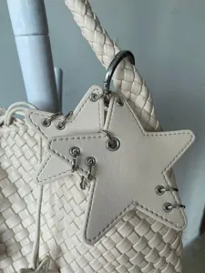 Detail shot of beige woven leather handbag featuring unique star charm and metal ring details.