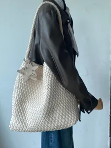 Detailed side view of off-white woven leather shoulder tote bag featuring a star charm.