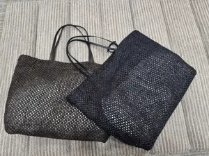 Two black and brown woven straw tote bags featuring slim shoulder straps for daily wear.