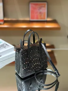 Black leather laser-cut tote bag with top handles and shoulder strap for women fashion.