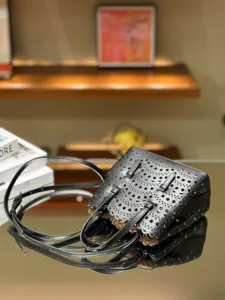 Black leather laser cut tote bag stylish shoulder handbag with scalloped edge design.