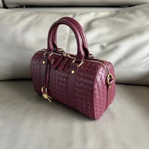 Leather woven Boston handbag detail shot, vintage burgundy pillow bag with dual top handles.