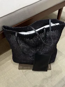 Minimalist black woven raffia tote bag with leather handles and pouch, stylish and large.