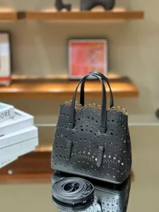 Detail shot of black leather laser-cut tote bag with intricate floral patterns and top handles.