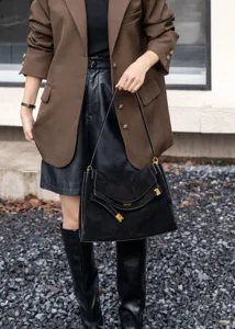 Detail view of the retro black suede shoulder tote bag with metallic clasp and strap.