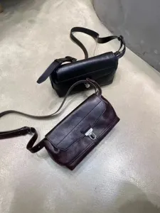 Detailed view of genuine leather messenger crossbody bags in black and dark brown with metal lock.