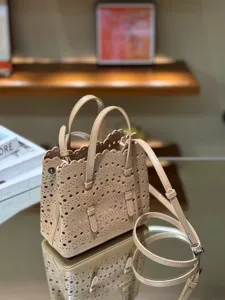 Elegant leather laser-cut tote bag with top handles and shoulder strap for women.