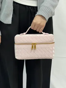 Close-up view of the pink woven cosmetic bag featuring glossy texture and gold dual zippers.