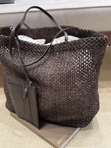 Detailed view of dark brown woven raffia tote bag with leather straps and attached pouch.