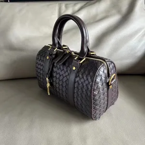 Close-up of a dark brown woven leather Boston handbag featuring premium texture and hardware details.