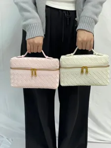 Glossy woven vanity bag cosmetic handbag with top handle and double zipper closure.