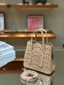 Detailed shot of beige leather laser-cut tote bag with delicate scalloped trim and shoulder strap.