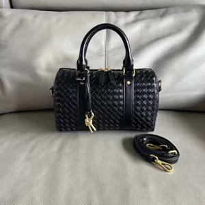 Black leather woven boston handbag with top handles and strap. Classic chic design.