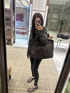 Dark brown woven leather tote bag shoulder style worn by model in minimalist casual design
