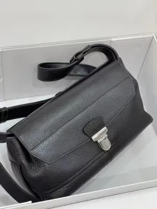 Close-up detail of black leather messenger bag featuring silver hardware and textured finish.