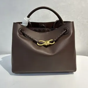 Brown smooth calfskin top handle bag featuring elegant knot hardware and woven details.