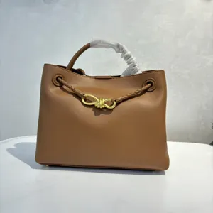 Brown smooth calfskin handbag with elegant metal bow hardware and stylish braided handle design.