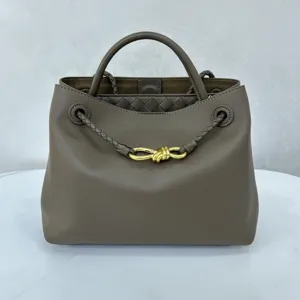 Luxurious smooth calfskin brown handbag featuring stylish woven trim and gold metal knot hardware.