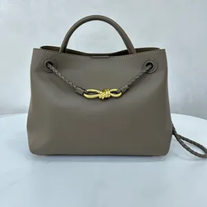 Brown leather handbag detail featuring stylish golden metal knot hardware and braided handles.