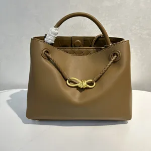 Detailed view of the brown leather handbag showing gold bow hardware and braided handles.