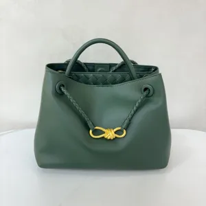 Dark green calfskin handbag detail, featuring gold-toned metal knot and braided strap design.