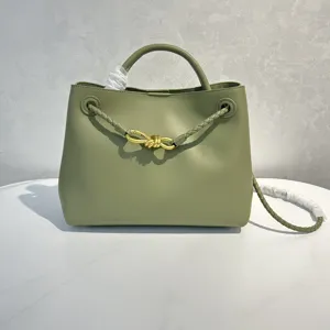 Olive green leather handbag featuring stylish gold knot hardware and elegant braided strap details.