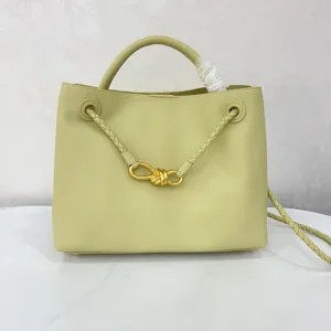 Light green leather bucket bag with braided handle and gold knot hardware detail for daily use.