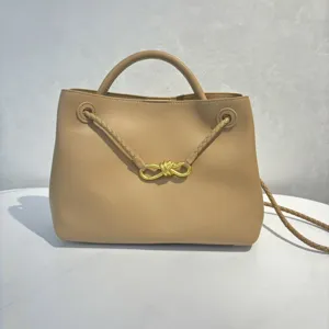 Detailed view of the beige leather handbag featuring elegant braided straps and gold bow hardware.
