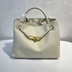 Off-white calfskin handbag with golden bow hardware and woven strap detailing for women.