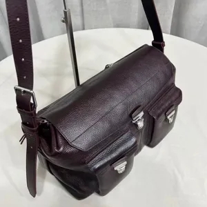 Detailed view of the dark burgundy leather messenger bag featuring multi pockets and metal buckles.