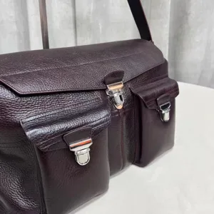 Detailed view of the dark burgundy leather messenger bag featuring multiple pockets and metal hardware.