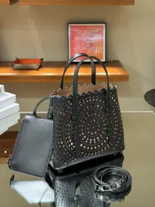 Black leather laser-cut tote bag with scalloped edge, companion pouch, and detachable strap.