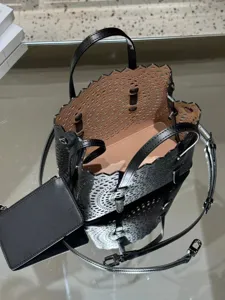 Detailed view of black laser cut leather tote bag with pink lining and stylish cutout design.