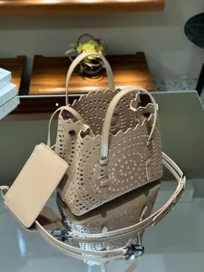 Detailed view of the beige laser-cut leather tote bag with top handles and strap.