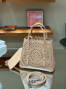 Beige leather laser-cut tote bag with top handles, removable strap and pouch chic.