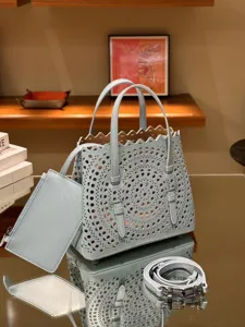Light blue leather laser-cut tote bag with handle, matching pouch, and detachable shoulder strap.