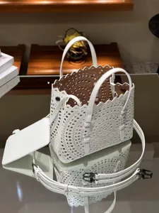 White leather laser cut tote bag detail view, stylish perforated design with top handles.