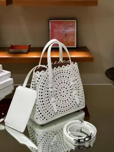 White laser-cut leather tote bag with top handles, detachable strap and matching pouch.