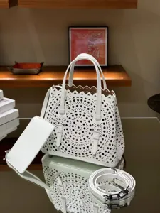 White leather laser-cut tote bag with top handles, matching pouch, and detachable strap.
