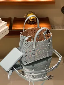 Light blue laser cut leather tote bag with scalloped edge, matching pouch and strap for women.
