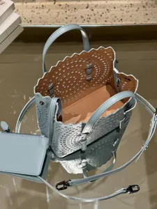 Detail view of light blue leather laser-cut tote bag with scalloped trim and matching pouch.