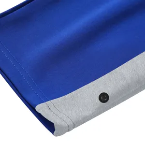 Gedetailleerd overzicht heren sportbroek, blauwe body met grijze kleurblok en knoopmanchet.