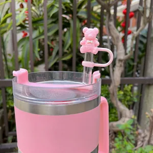 Detailed shot of a pink insulated cup with an adorable smiling bear silicone straw cap.